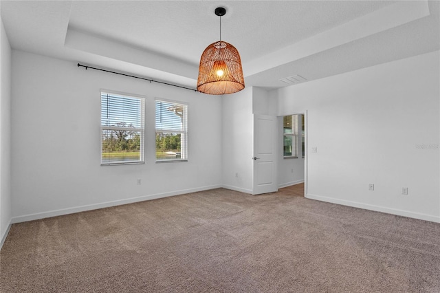 empty room featuring baseboards, a raised ceiling, visible vents, and carpet flooring