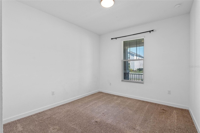 carpeted empty room featuring baseboards