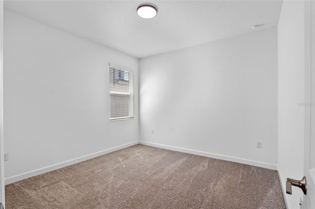 carpeted spare room featuring baseboards