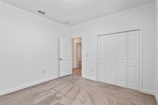 unfurnished bedroom with a closet, carpet flooring, baseboards, and visible vents