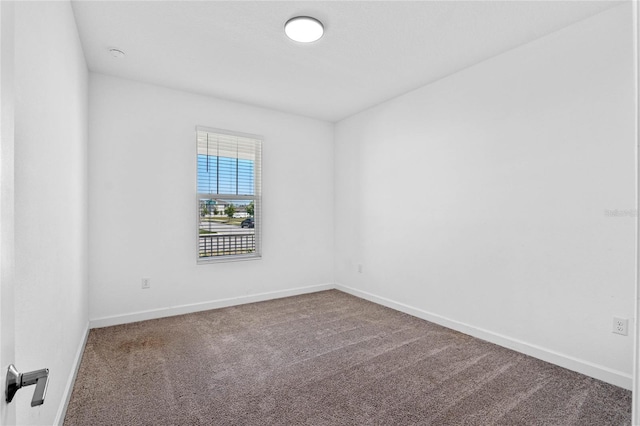 spare room with baseboards and carpet floors