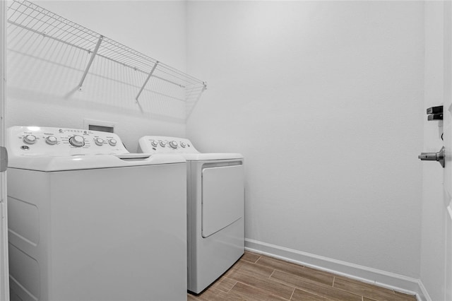 laundry room with laundry area, wood finish floors, baseboards, and washing machine and clothes dryer