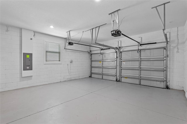 garage featuring electric panel, concrete block wall, and a garage door opener