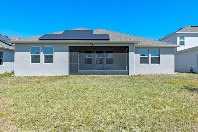 back of house featuring stucco siding, a lawn, roof mounted solar panels, and a sunroom