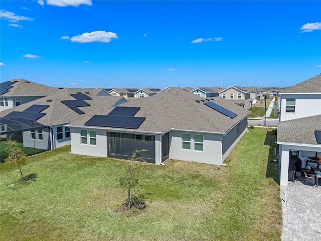 back of house with a residential view, roof with shingles, stucco siding, a yard, and a sunroom