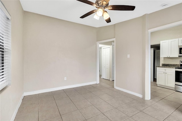 interior space with light tile patterned floors, ceiling fan, and baseboards