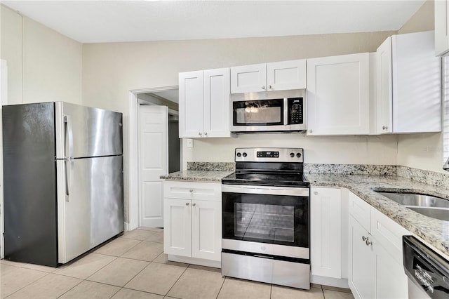 kitchen with white cabinets, appliances with stainless steel finishes, light stone countertops, a sink, and light tile patterned flooring