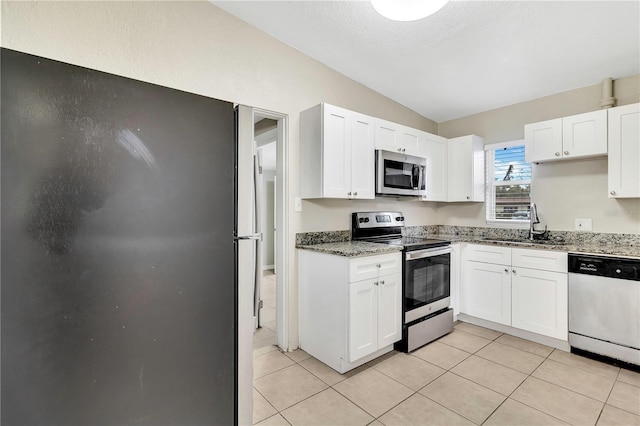 kitchen with white cabinets, stainless steel appliances, a sink, and light tile patterned flooring