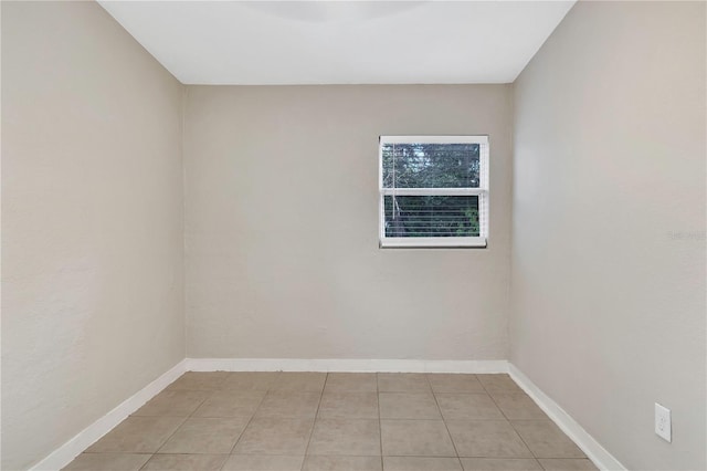 empty room with light tile patterned floors and baseboards