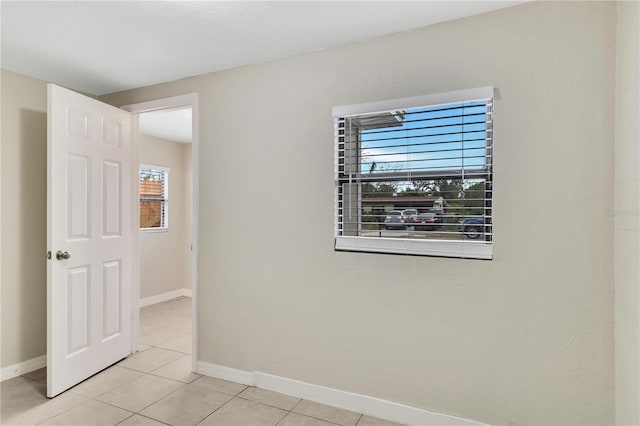 unfurnished room with light tile patterned floors and baseboards