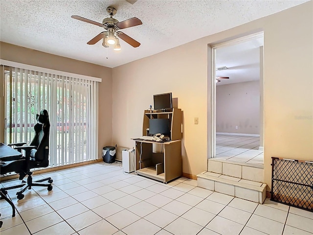 home office with a textured ceiling, baseboards, a ceiling fan, and light tile patterned flooring