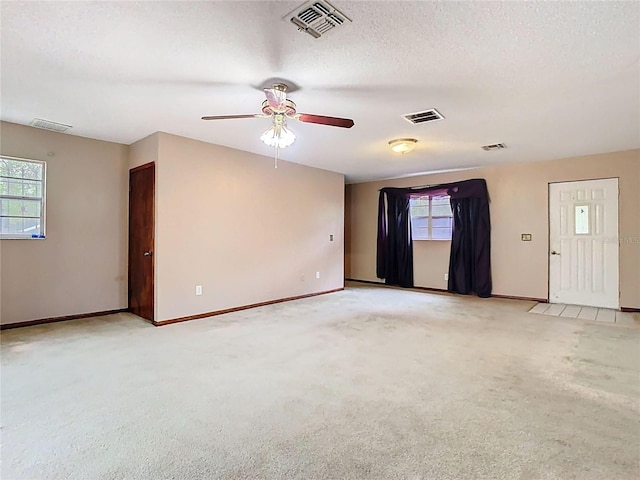 empty room featuring visible vents, a textured ceiling, and light colored carpet