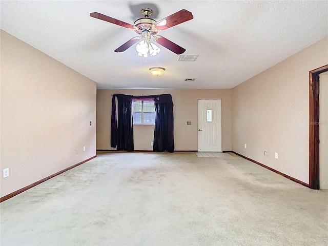 empty room featuring light carpet, baseboards, visible vents, and ceiling fan