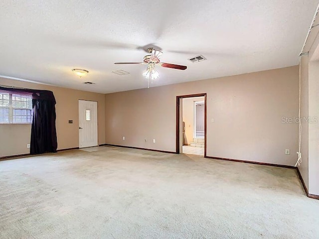 unfurnished room with light colored carpet, visible vents, ceiling fan, a textured ceiling, and baseboards