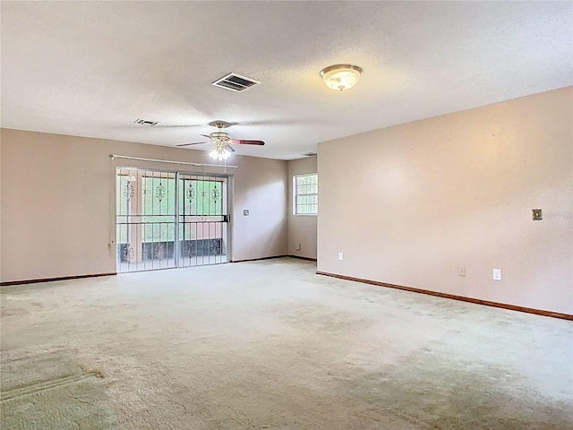 empty room with light carpet, baseboards, visible vents, and a ceiling fan