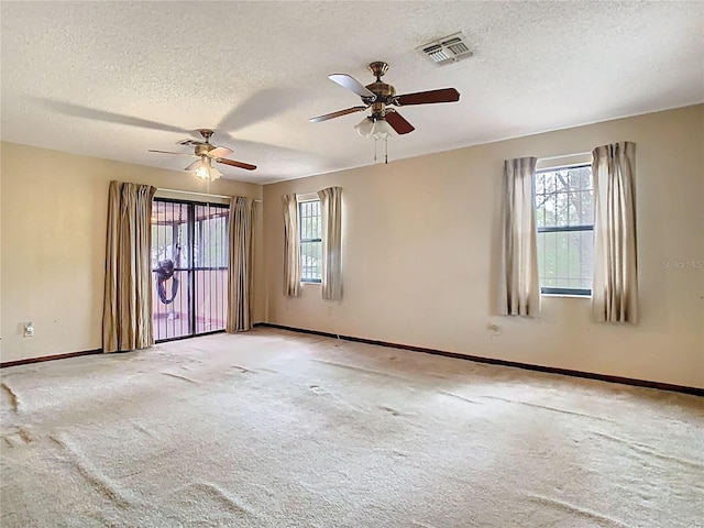 carpeted empty room featuring a textured ceiling, visible vents, and baseboards