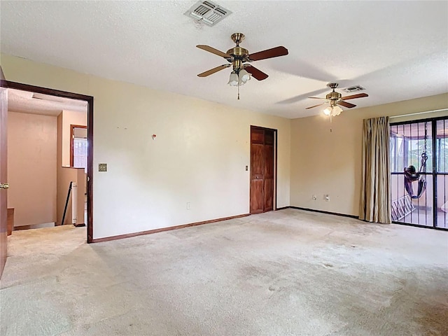 unfurnished room with baseboards, visible vents, a textured ceiling, and light colored carpet