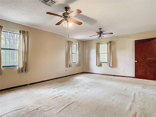 carpeted spare room featuring baseboards, visible vents, and a textured ceiling