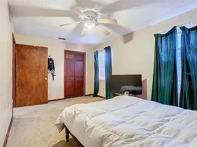 bedroom with visible vents, baseboards, a ceiling fan, light colored carpet, and a textured ceiling