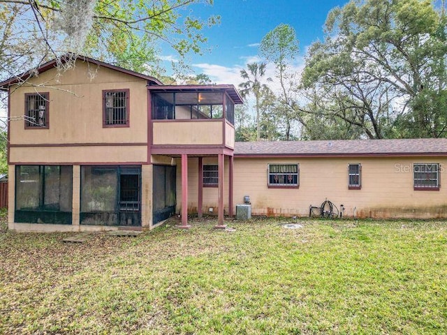 back of house with a lawn, a sunroom, and central air condition unit