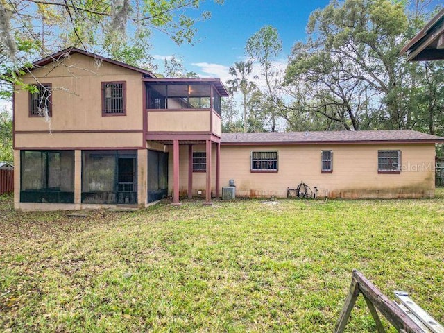 rear view of property featuring a sunroom, cooling unit, and a yard