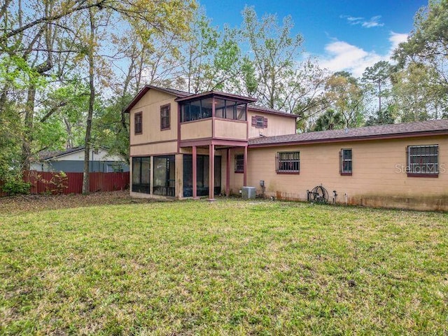 rear view of property with a sunroom, fence, central air condition unit, and a lawn