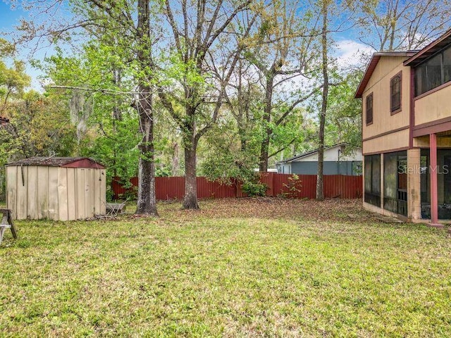 view of yard with fence, an outdoor structure, and a storage unit