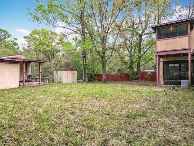 view of yard featuring an outbuilding, fence, central AC unit, and a storage unit