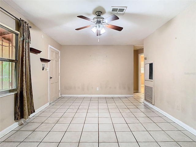 spare room featuring a ceiling fan, visible vents, baseboards, and light tile patterned floors