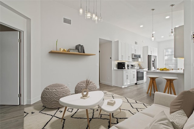 living room with recessed lighting, visible vents, baseboards, and light wood-style flooring