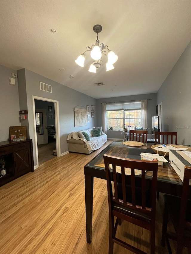 dining area with lofted ceiling, light wood-style floors, visible vents, and a chandelier