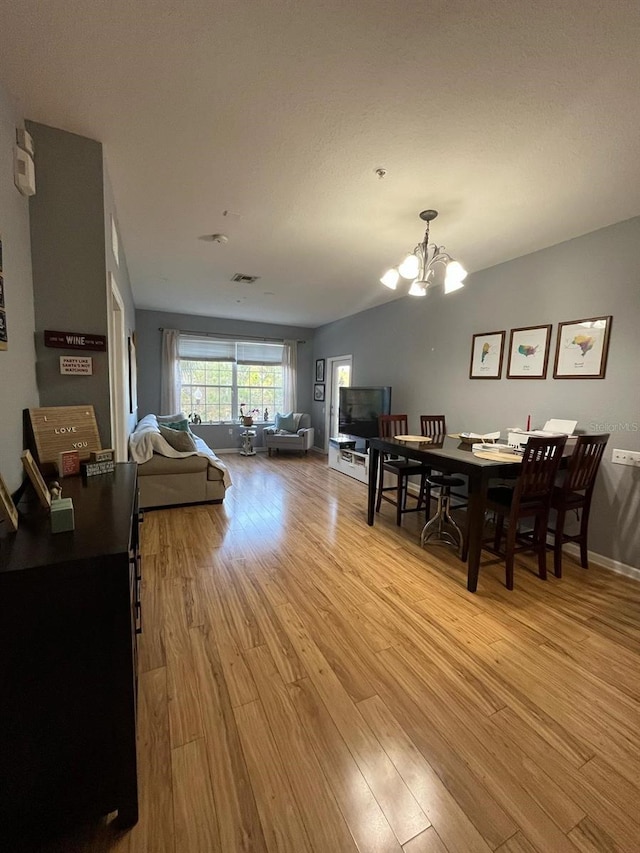 dining room featuring visible vents, baseboards, a notable chandelier, and wood finished floors