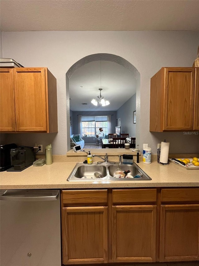 kitchen featuring dishwasher, light countertops, an inviting chandelier, and a sink