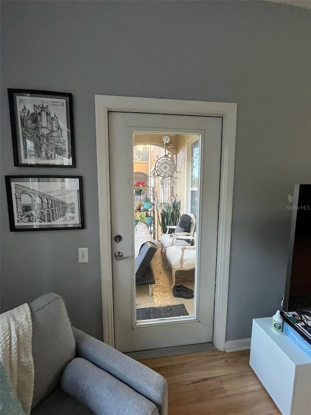 doorway with baseboards and wood finished floors