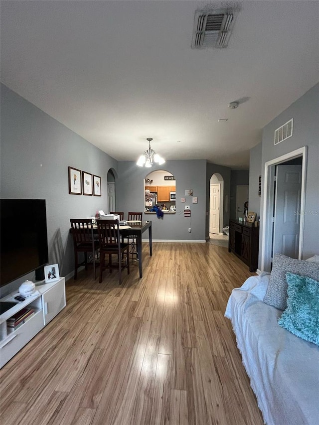 living area featuring wood finished floors, arched walkways, visible vents, and a chandelier