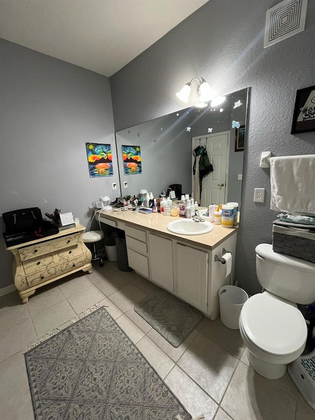 bathroom with tile patterned floors, visible vents, toilet, vanity, and a textured wall