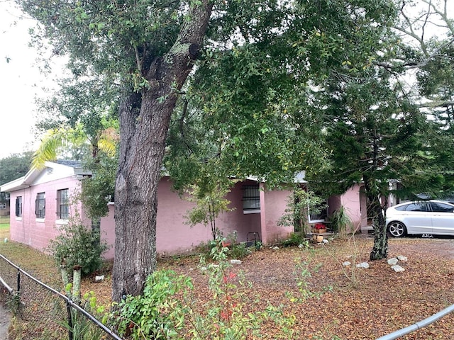 view of side of property featuring fence and stucco siding