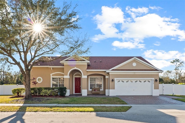 view of front of house featuring a garage, fence, decorative driveway, a gate, and stucco siding