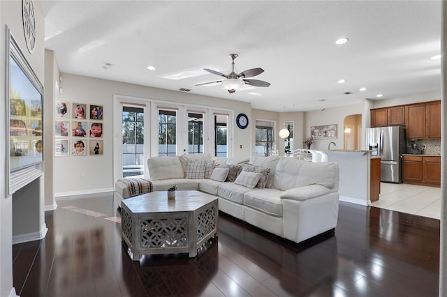 living area featuring arched walkways, recessed lighting, visible vents, baseboards, and light wood-style floors