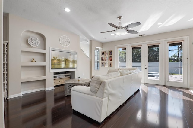 living room featuring baseboards, built in features, dark wood-style flooring, a textured ceiling, and french doors