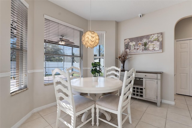 dining area with light tile patterned floors, baseboards, and arched walkways