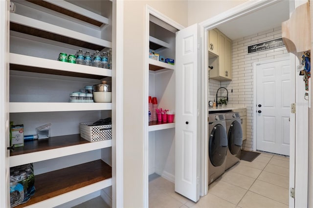 clothes washing area with a sink, light tile patterned floors, and washer and dryer