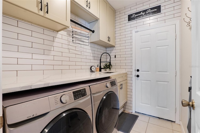 washroom with light tile patterned floors, independent washer and dryer, a sink, and cabinet space