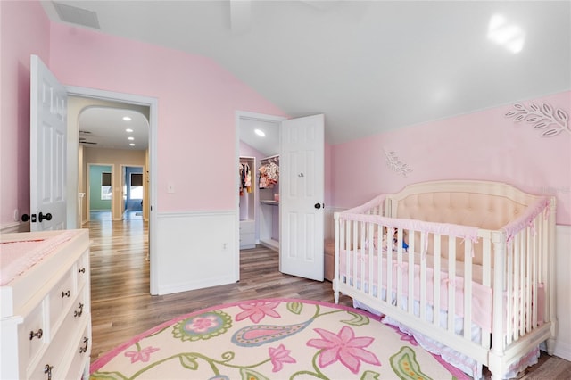 bedroom with lofted ceiling, wood finished floors, visible vents, a closet, and a walk in closet