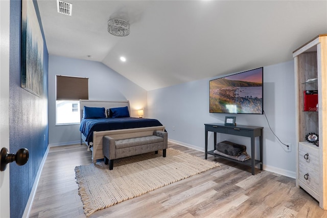 bedroom featuring lofted ceiling, light wood-style flooring, visible vents, and baseboards