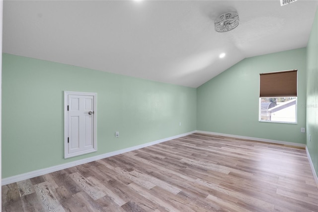 additional living space with light wood-style floors, vaulted ceiling, and baseboards