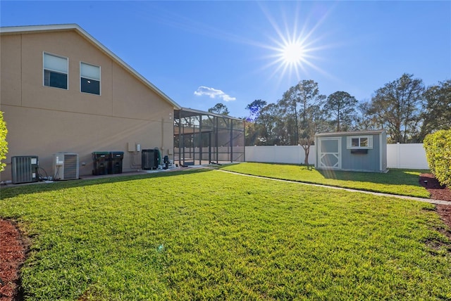 view of yard with central AC unit, a fenced backyard, an outbuilding, a lanai, and a shed