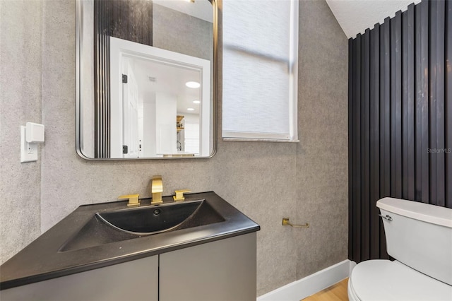 bathroom with toilet, baseboards, and vanity