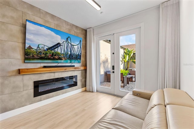 living room with a glass covered fireplace, wood finished floors, and french doors