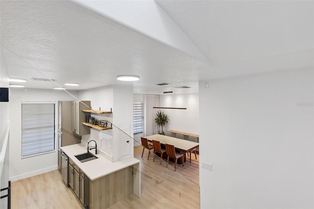 kitchen featuring open shelves, light wood finished floors, a sink, and light countertops